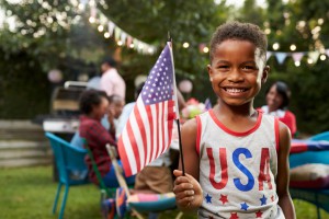 Young black boy holding flag at 4th July family garden